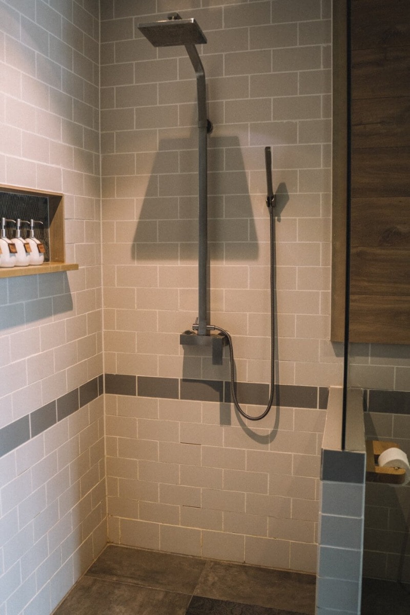 Polu-otvorena tuš kabina u kupatilu s pločicama krem boje